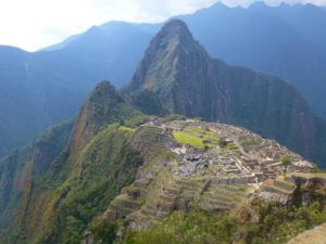 Inca ruins on the top of a mountain with other green mountains behind